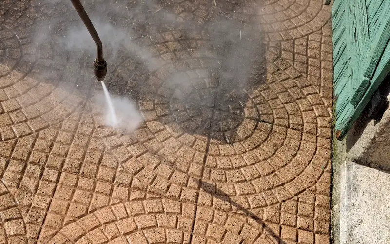Lance haute pression nettoyant une terrasse en pavés autobloquants