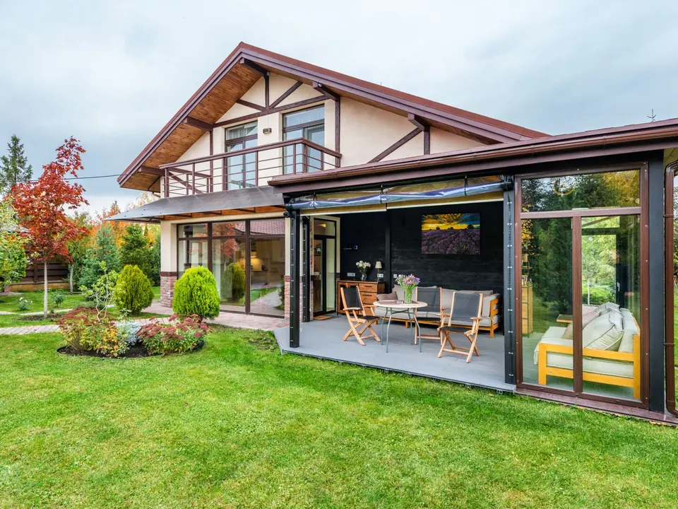 Jardin aménagé par un paysagiste : pelouse tondue, massif fleuri, arbustes taillés et terrasse abritée le long de la maison